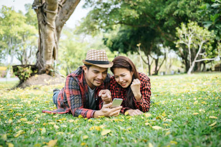 Romantic couple of young people lying on grass in park.の写真素材