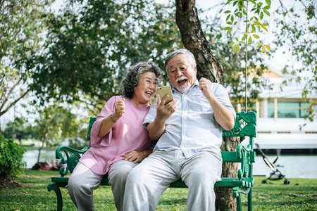 Senior couple taking a selfie photo with smart phone in a parkの写真素材