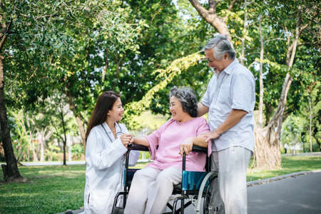 Nurse looking at elderly patient in a wheelchair. Doctor talking to old disabledの写真素材