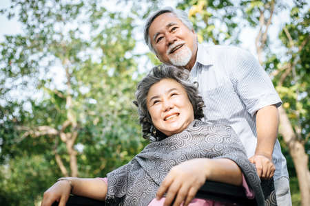 Senior man caring for  disabled wife in his wheelchair.の写真素材