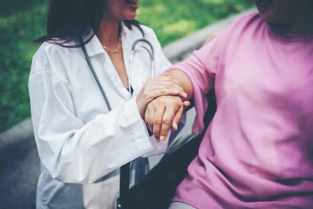 Nurse looking at elderly patient in a wheelchair. Doctor talking to old disabledの写真素材