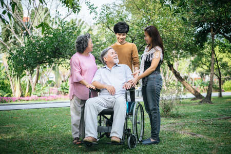 cheerful disabled grandfather in wheelchair welcoming his happy Familyの写真素材