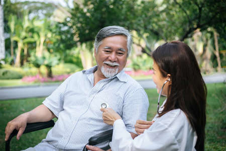 Nurse looking at elderly patient in a wheelchair. Doctor talking to old disabledの写真素材