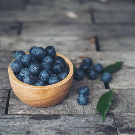 Fresh plums  in wooden bowl on old wooden backgroundの写真素材