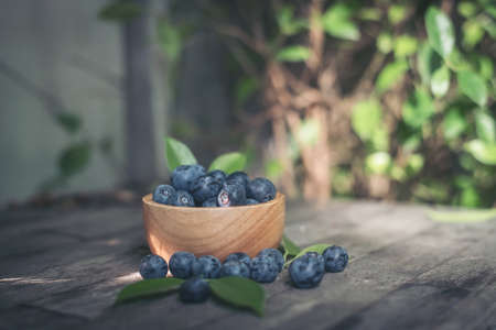 Fresh plums  in wooden bowl on old wooden backgroundの写真素材