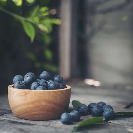 Fresh plums  in wooden bowl on old wooden backgroundの写真素材