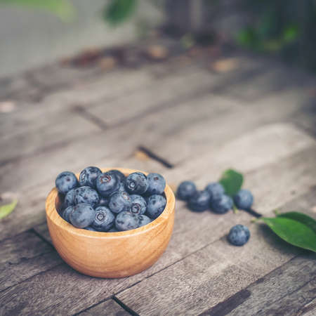 Fresh plums  in wooden bowl on old wooden backgroundの写真素材