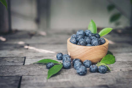 Fresh plums  in wooden bowl on old wooden backgroundの写真素材