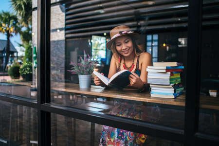 Young woman  reading book and fresh cup of coffee on the tableの写真素材