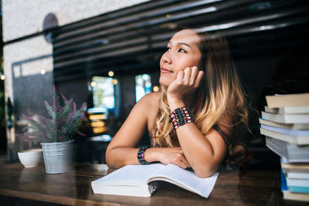 Young woman  reading book and fresh cup of coffee on the tableの写真素材