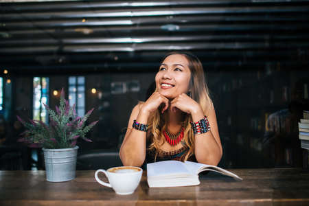Young woman  reading book and fresh cup of coffee on the tableの写真素材