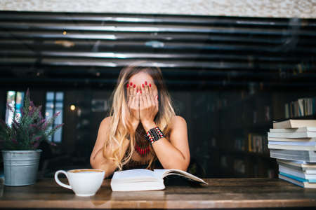 Young woman  reading book and fresh cup of coffee on the tableの写真素材