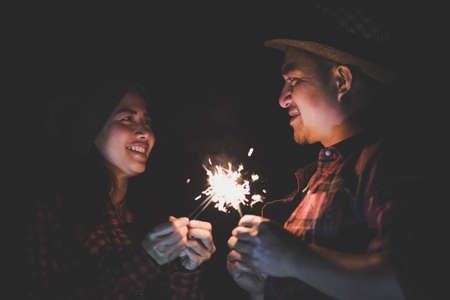 The happy couple hold a firework sticks. evening night time