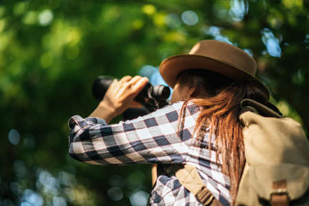 Happy freedom young woman watching wildlife with binoculars in nature park autumn, Tourist traveler backpack with copy space ,travel concept.の写真素材
