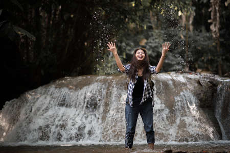 Young woman having fun under waterfalls in the forestの写真素材