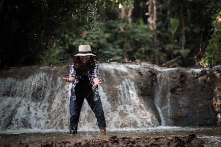 Young woman having fun under waterfalls in the forestの写真素材