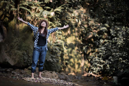 happy young woman raising her arms to greet the sun at the forestの写真素材