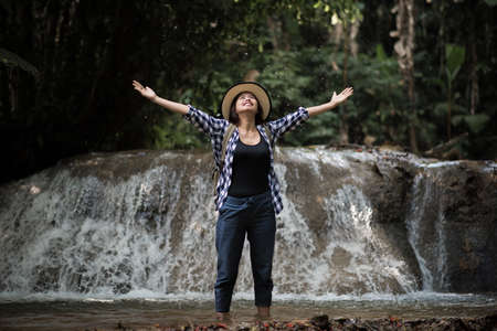 Young woman having fun under waterfalls in the forestの写真素材