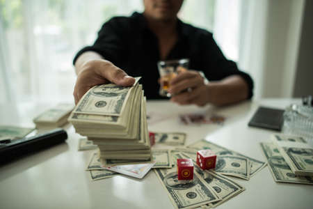 Businessman sitting in a business center bar smoking cigar and drinking whiskey and money on the table.の写真素材