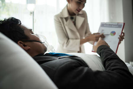 Business man with suit working with oxygen mask in the office. Sick man work in the office aloneの写真素材