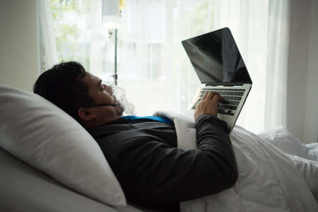 Business man with suit working with oxygen mask in the office. Sick man work in the office aloneの写真素材