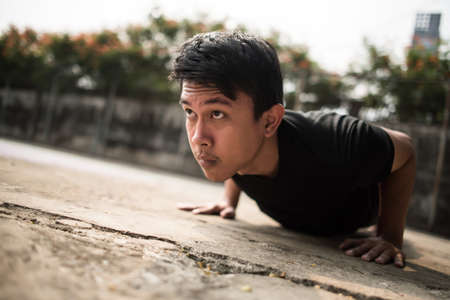 Close-up image of a young sportsman doing push-ups outsideの写真素材