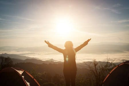 Happy Young Woman Hiker With Open Arms Raised at Sunset on Mountain Peakの写真素材