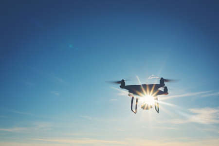 White drone hovering in a bright blue skyの写真素材