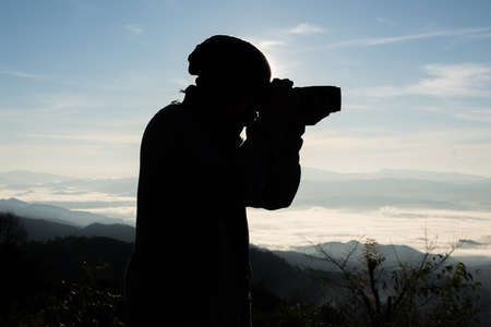 Silhouette  young photographer holding a camera with landscape in the mountain.の写真素材