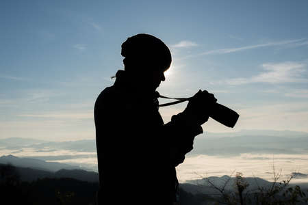 Silhouette  young photographer holding a camera with landscape in the mountain.の写真素材