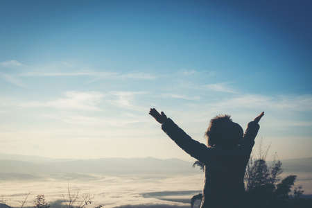 Happy Young Woman Hiker With Open Arms Raised at Sunset on Mountain Peakの写真素材