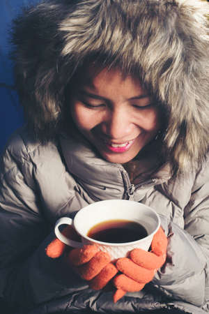 Smiling woman with cup of coffee in the winter parkの写真素材