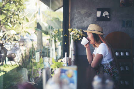 Beautiful cute girl in the cafe near the window with coffee smilingの写真素材