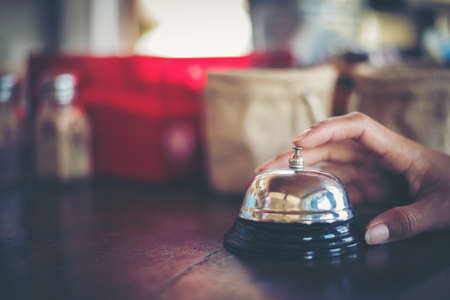 woman hand ringing silver service bell on coffee shopの写真素材