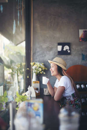 Beautiful cute girl in the cafe near the window with coffee smilingの写真素材