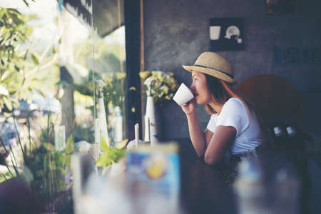Beautiful cute girl in the cafe near the window with coffee smilingの写真素材