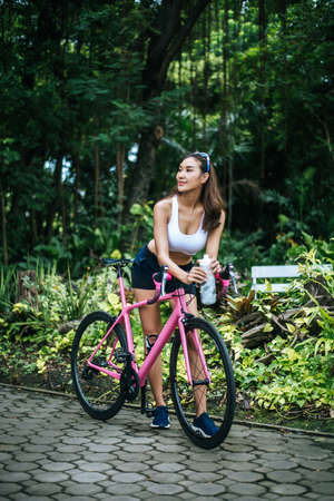 Portrait of young beautiful woman with pink bike in the park. Actractive healthy woman.の写真素材