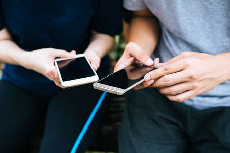 Close up of friends hands play with smartphone together.の写真素材