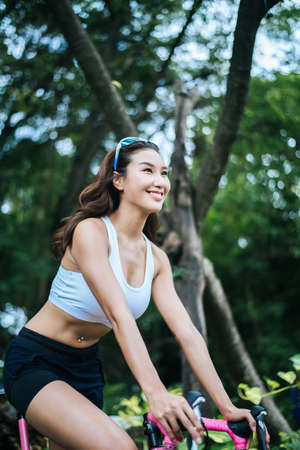 Close up of attractive woman riding a road bike in the park. Health and sport concept.の写真素材