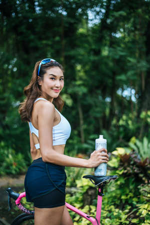 Portrait of young beautiful woman with pink bike in the park. Actractive healthy woman.の写真素材