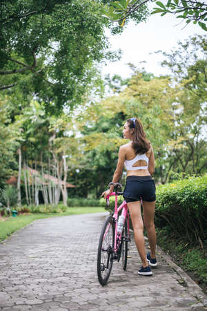 Portrait of young beautiful woman with pink bike in the park. Actractive healthy woman.の写真素材