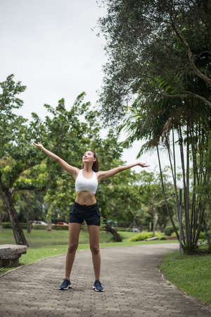 Young sport woman runner stretching body before run on track in the park.の写真素材