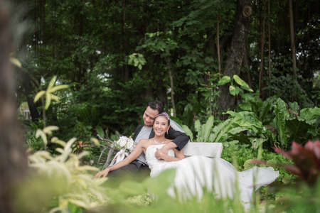 Bride and groom are sitting on branch with the green park on background.の写真素材