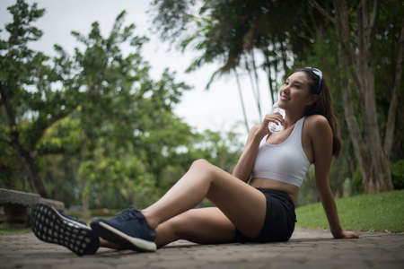 Young beautiful sport woman sit at the park after jog. Health and sport concept.の写真素材