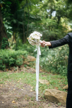 Close up of groom with beautiful bouquet in the hands for bride.の写真素材