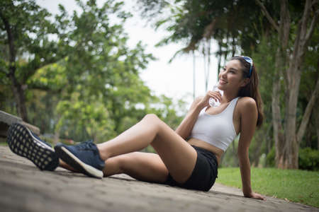Young beautiful sport woman sit at the park after jog. Health and sport concept.の写真素材