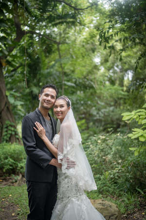 Bride and groom are standing with the green park on background.の写真素材