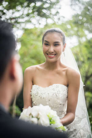 Portrait of love wedding day groom give flowers bouquet to his bride.の写真素材