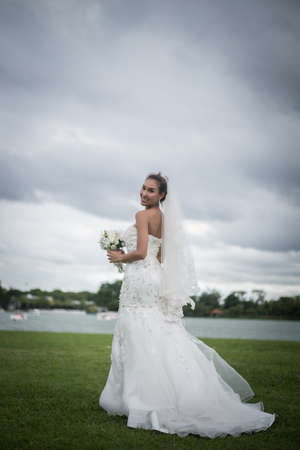 Beautiful Bride with wedding makeup and hairstyle. Gorgeous bride with wedding flowers bouquet, attractive woman in wedding dress.の写真素材