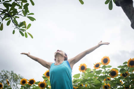 Beautiful woman with raising hands in a field of sunflowers in the summer. Women lifestyle concept.の写真素材